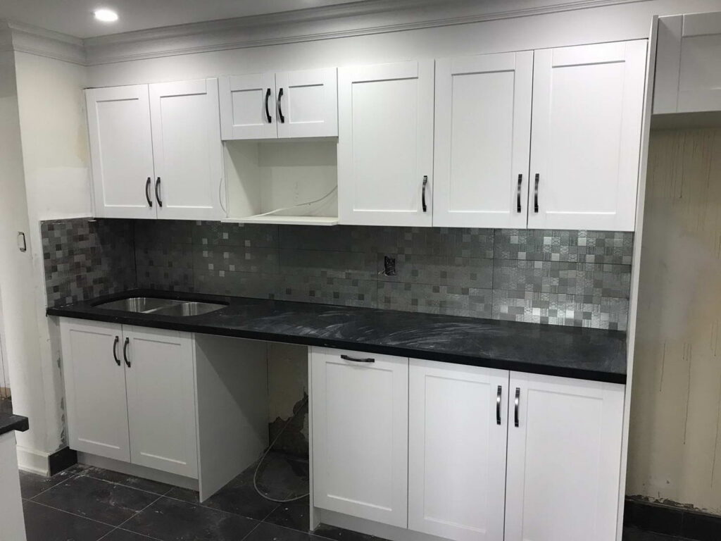 white kitchen cabinets with mosaic tile wall and black counter top 